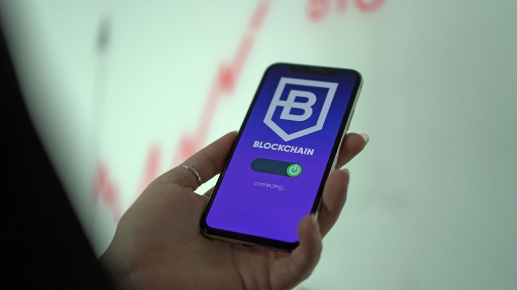Mão segurando um smartphone que exibe uma carteira digital de criptomoedas.