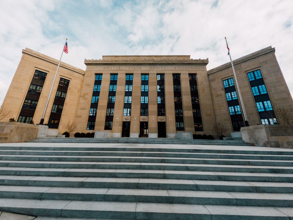 Edifício do Federal Reserve visto de baixo, com bandeiras dos Estados Unidos diante da fachada.